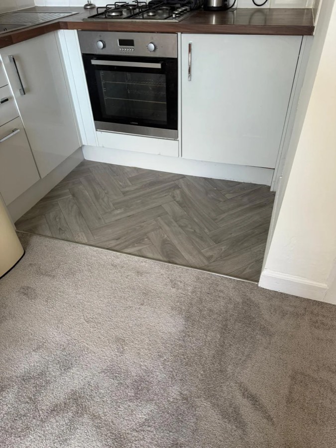 A & R Flooring job — grey herringbone LVT kitchen with new carpet through the doorway